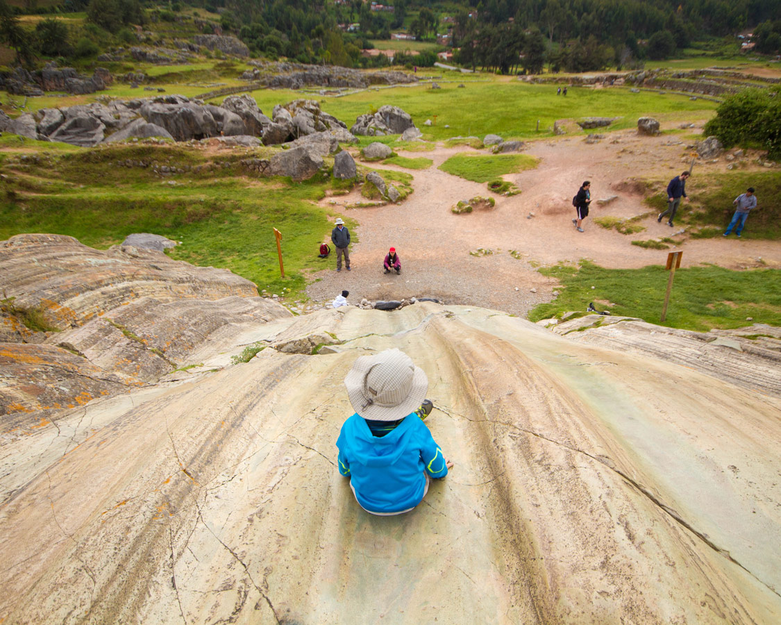A young boy prepares to slide down the rock slides in Sacsaywaman, one of the best things to see in Cusco Peru