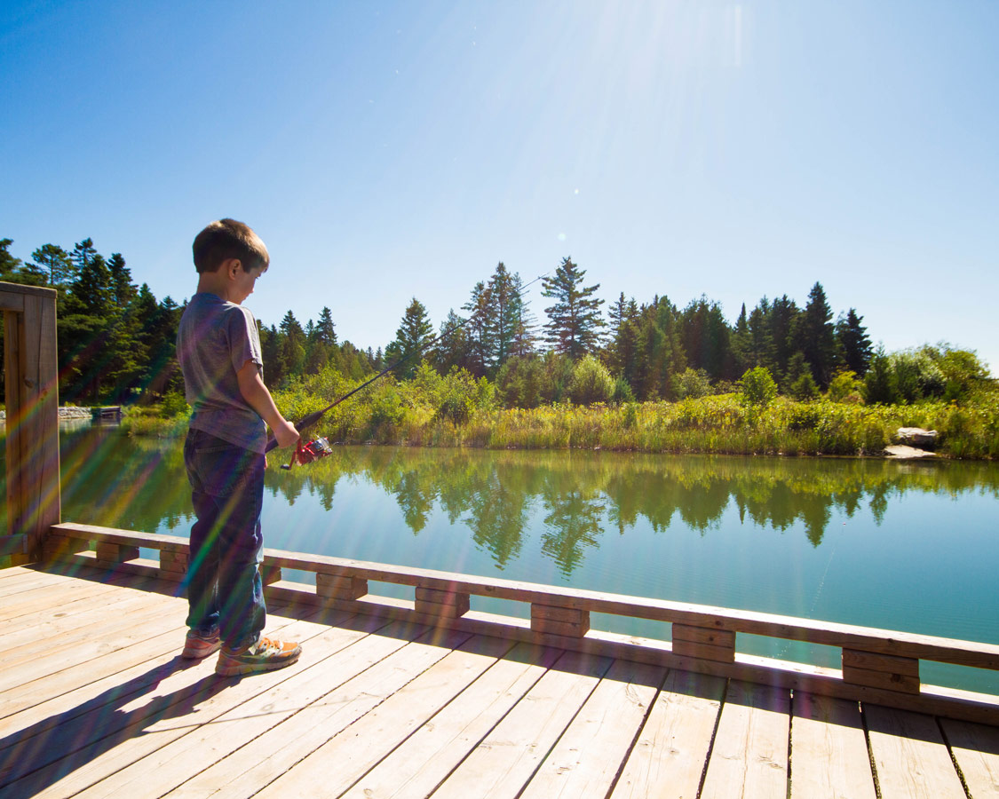 A young boy concentrates while fishing from the boardwalk in Providence Bay Manitoulin Island. Fishing for salmon is one of the top things to do on Manitoulin Island