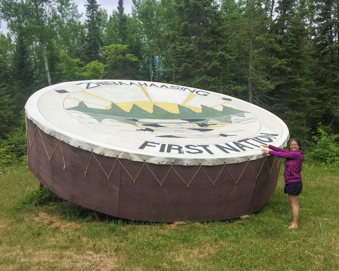 A woman smiles while banging the worlds largest Pow Wow drum in Sheshegwaning Manitoulin Island. A visit to Sheshegwaning is one of the best things to on Manitoulin Island