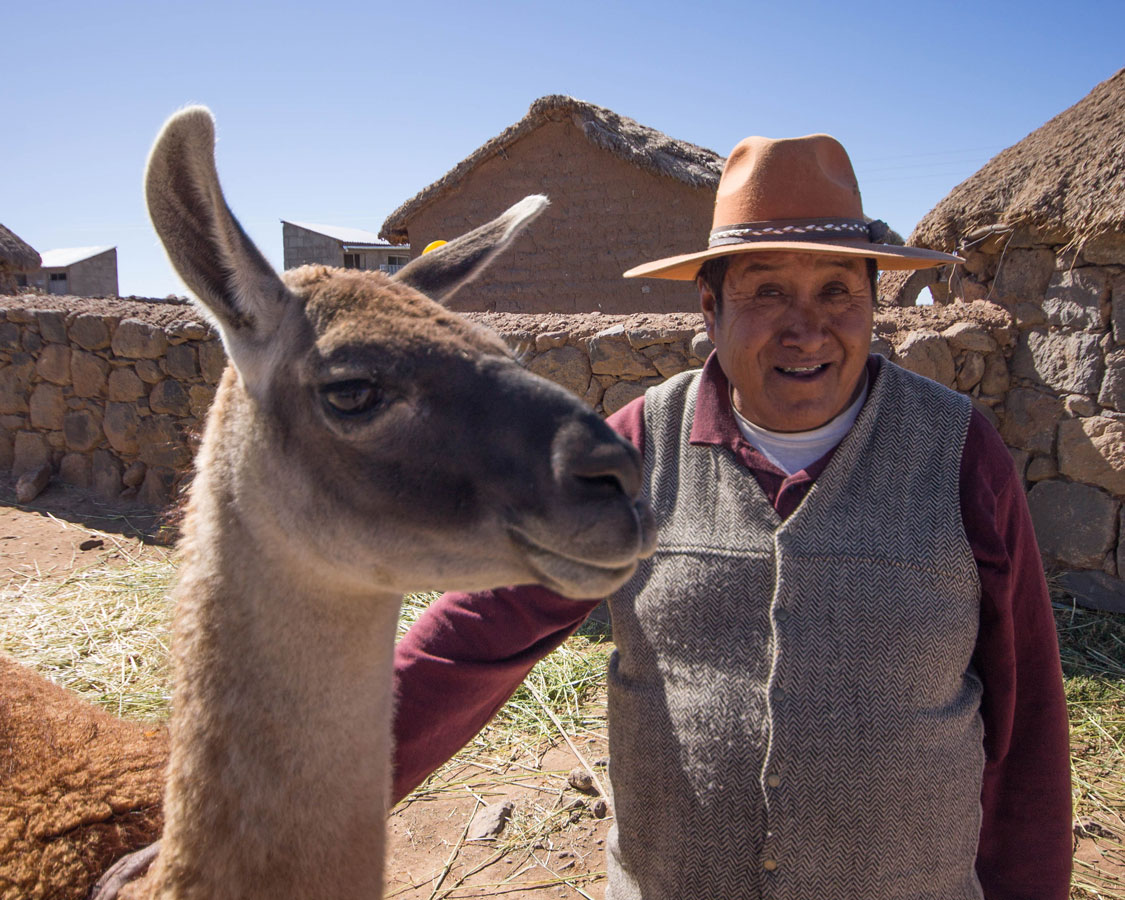 A Peruvian villager stands with a Llama in Peru with kids on a 14 day Peru itinerary