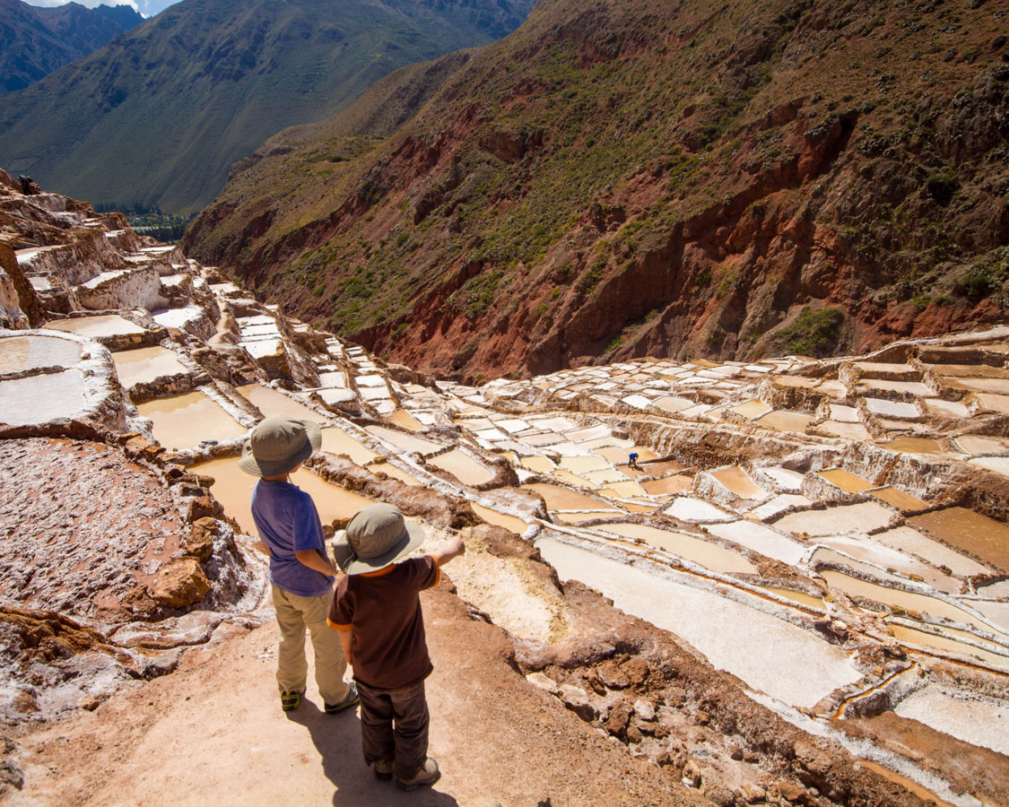 Looking out over the Salt Pans of Maras in the Sacred Valley of Peru with kids