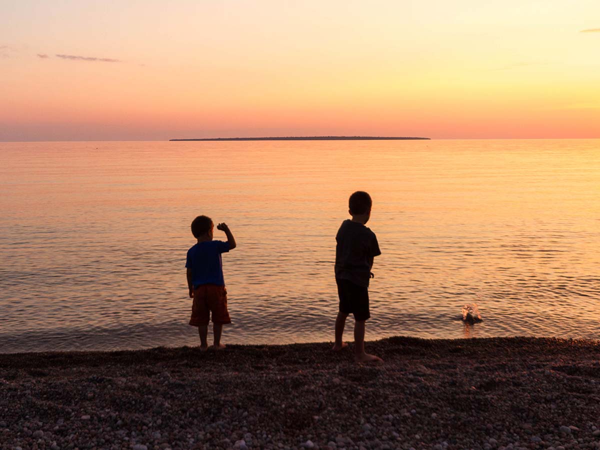 Boys throwing stones in the water at Lake-Superior Provincial Park in Ontario