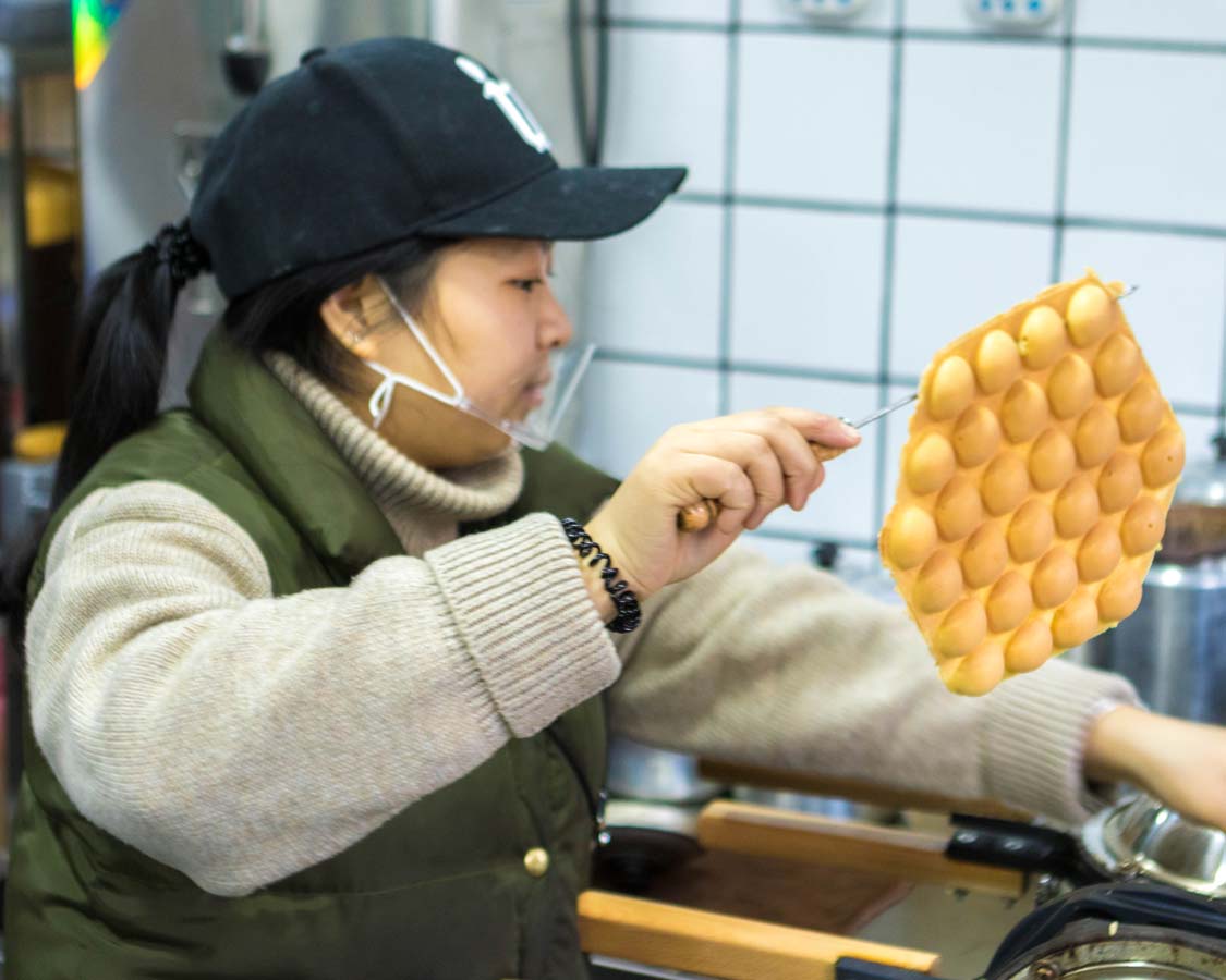 A shopkeeper at Law Kong Yuen Milk Tea Shop makes Shanghai style waffles on a food tour