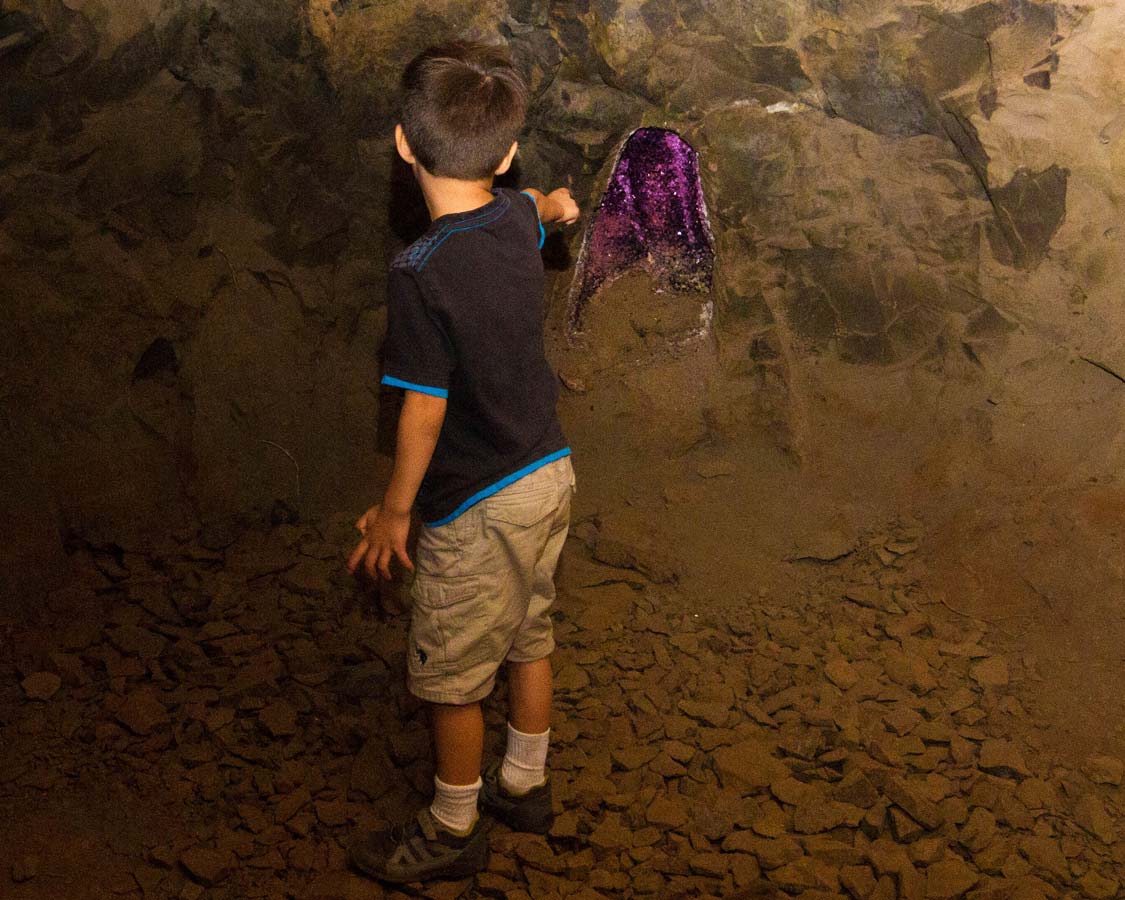 A young boy points at a purple geode in Wanda Mines near San Ignacio Argentina