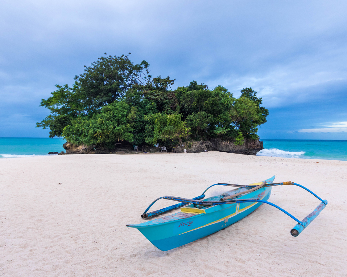 Paraw boat on the beach in front of a small island in Boracay Philippines