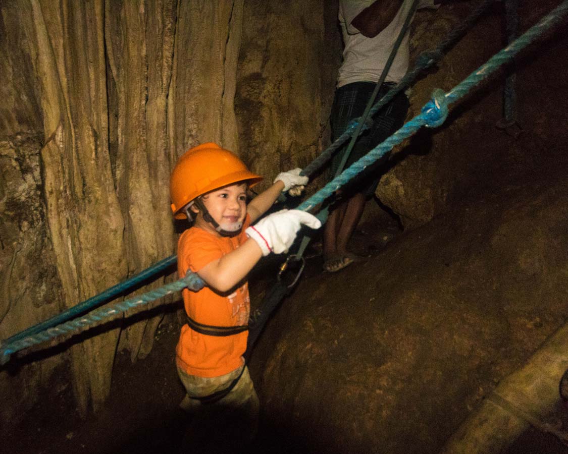 Boy climbing a rope ladder at Ugong Rock Caves in Palawan