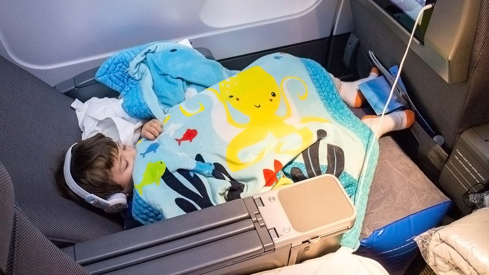 The 1st Class Kid Travel Pillow is an inflatable footrest for airplanes that fits in the space between seats in order to create a seamless reclining area for children to fly legs up. There are things that users need to know about flying with an airplane leg rest and we lay out everything we learned from our experience.