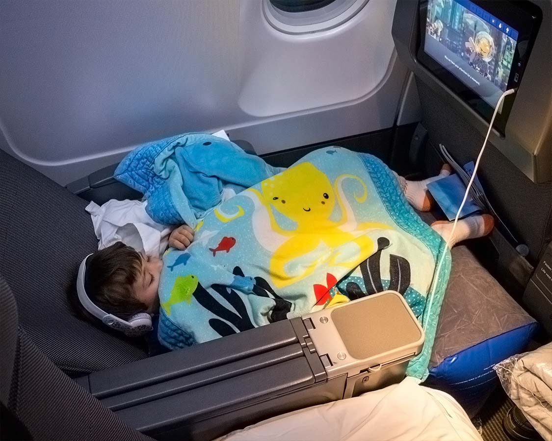 Boy sleeps on an airplane using children's travel pillow