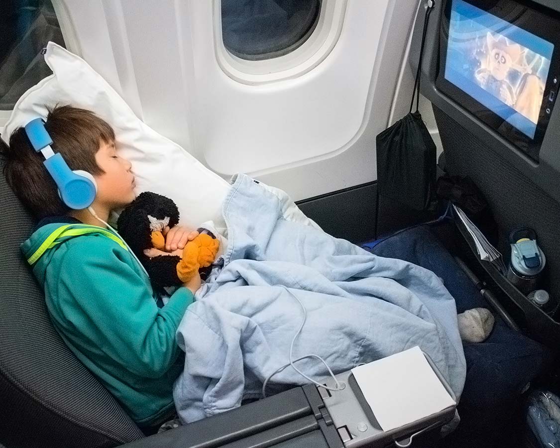 child sleeping on a plane using an inflatable footrest for plane