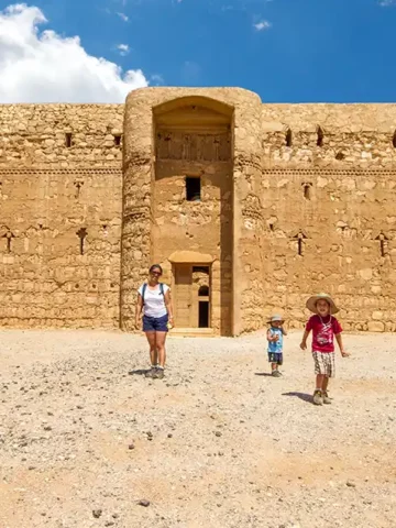 A family walking out of one of the most incredible Desert Castles in Jordan under a clear blue sky