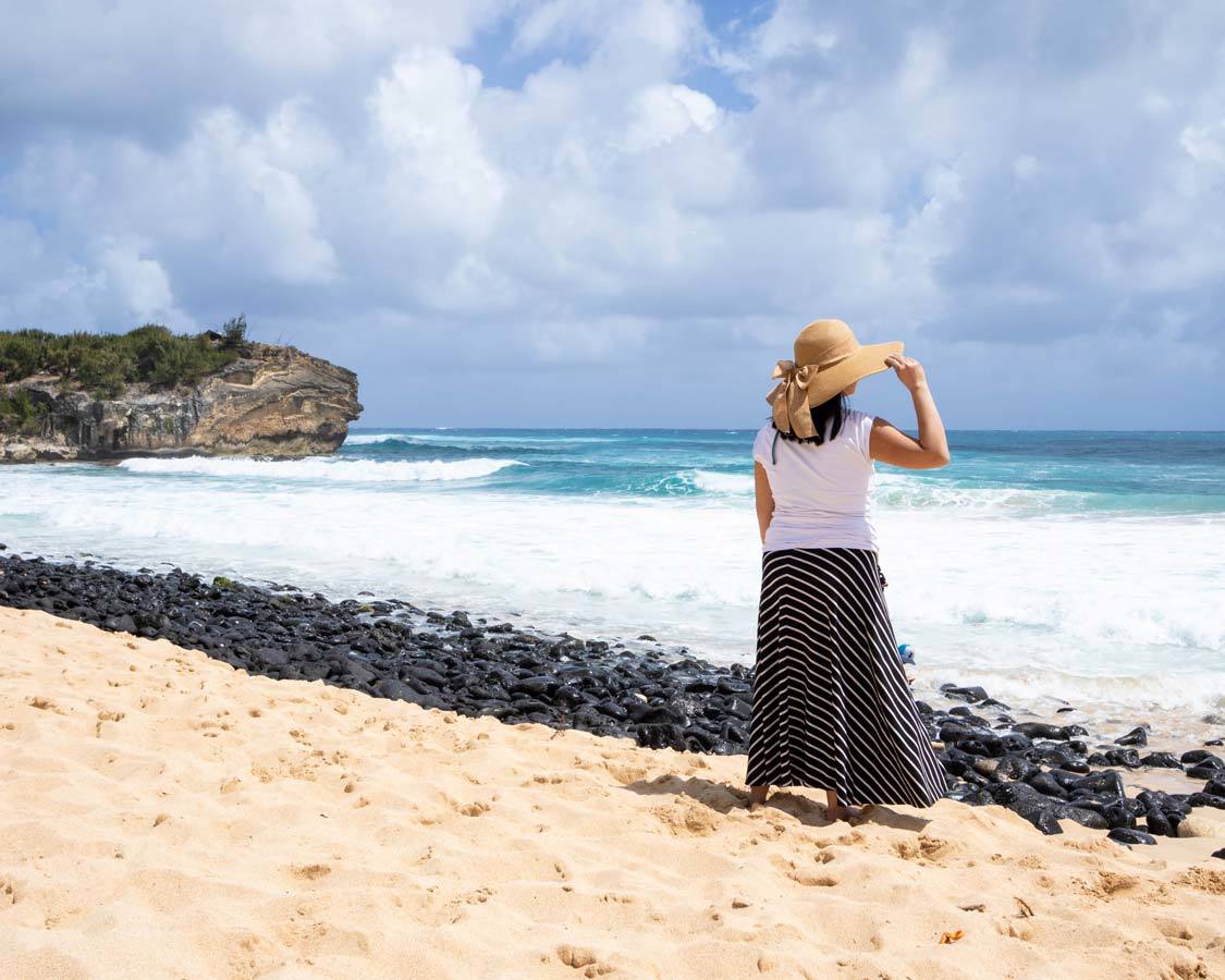  Plage du naufrage de Kauai avec une femme tenant un chapeau contre le vent choses à faire à Kauai avec des enfants