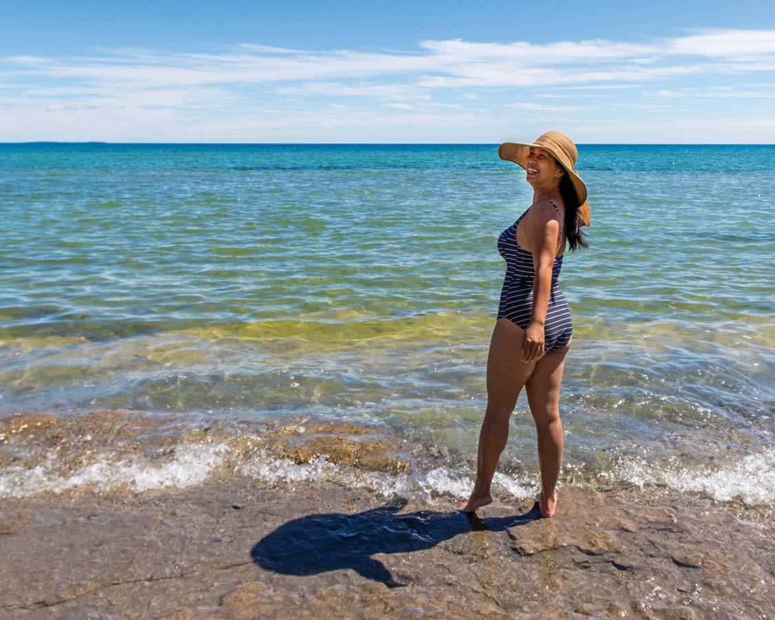 Woman wearing reef safe sunscreen standing on the beach smiling