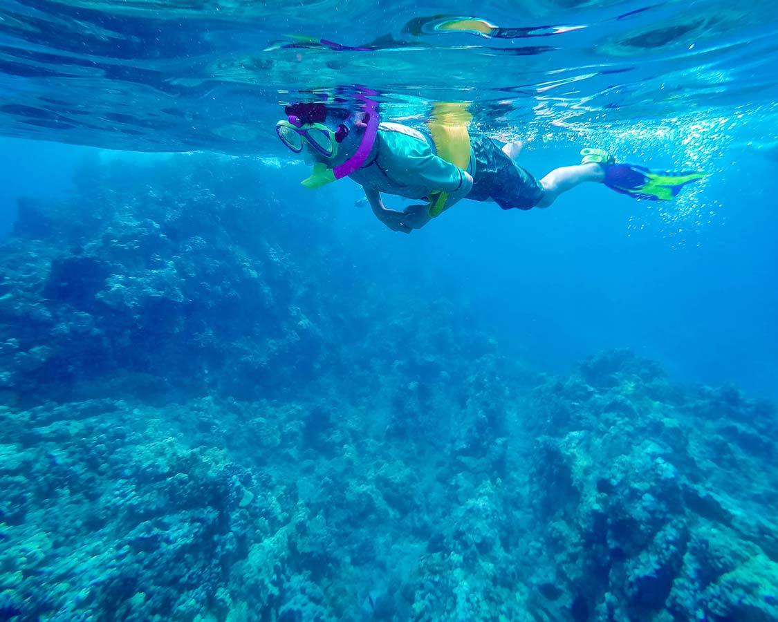 child snorkelling in Hawaii using coral reef safe sunscreen for kids