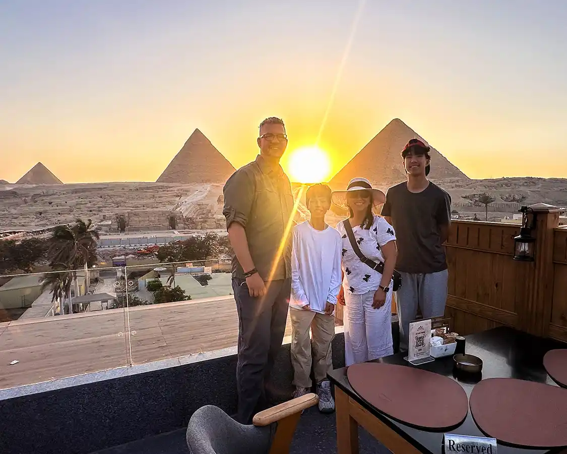A family poses for a photo at sunset over the Great Pyramids from Great Pyramid Inn