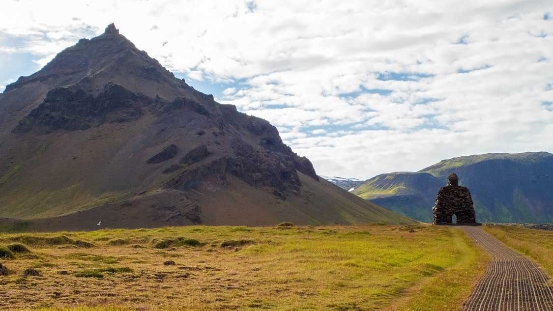 Statue of a giant beneath a cone mountain in Iceland