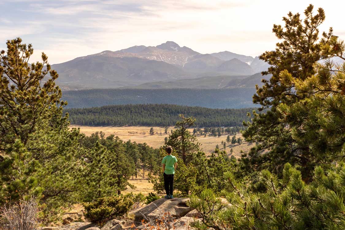 Boy looking out over fields and mountains at Rocky Mountain National Park in Colorado