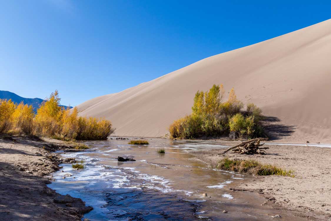 a frozen stream winds passed large sand dunes at Mesa Verde National Park in Colorado