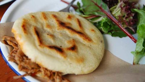 Colombian arepa stuffed with meet and cheese served with a salad