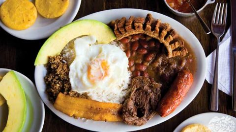 beans and rice topped with an egg, pork belly, chorizo, and served with sliced avocado