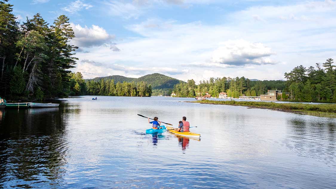 A father kayaks with his two children on Mirror Lake in Lake Placid New York