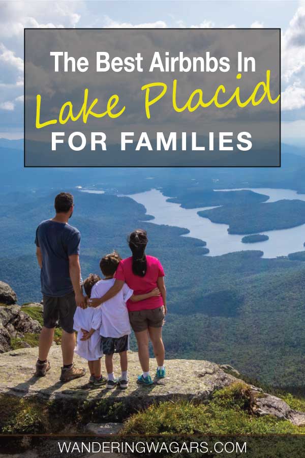 A family standing on top of a mountain looking out over a shimmering lake.