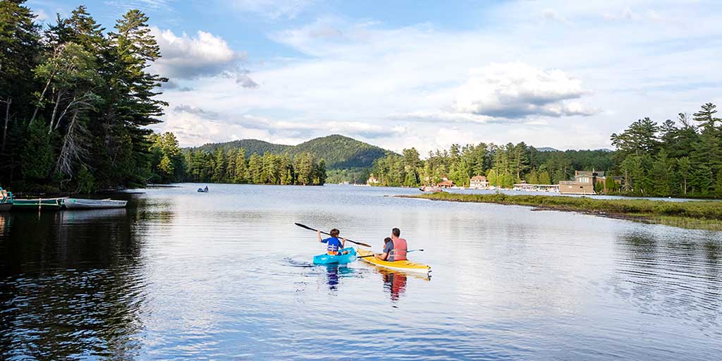 A father kayaks with his two children on Mirror Lake in Lake Placid New York