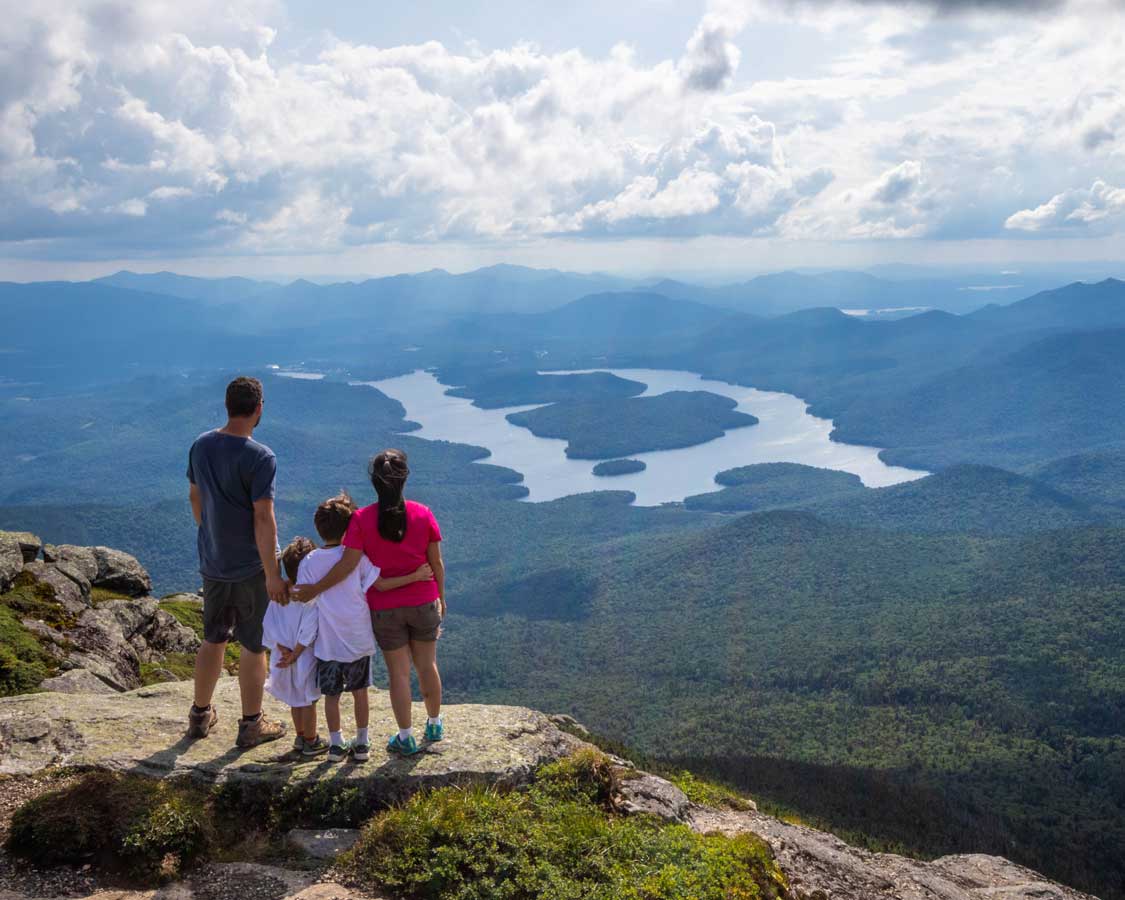 A family looks out over an island covered lake from atop a mountain