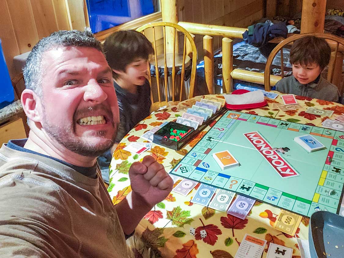 scowling father losing at board game to his children