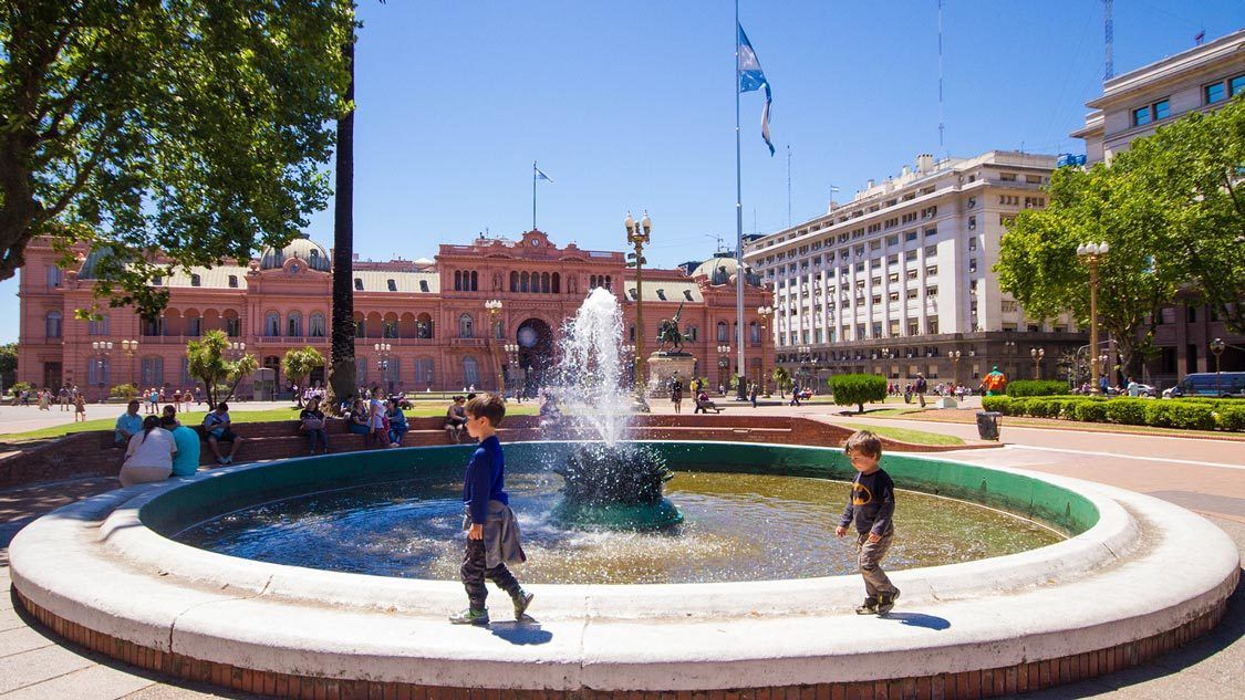 Two young boys walking around a fountain in Paza de Mayo in Buenos Aires with kids