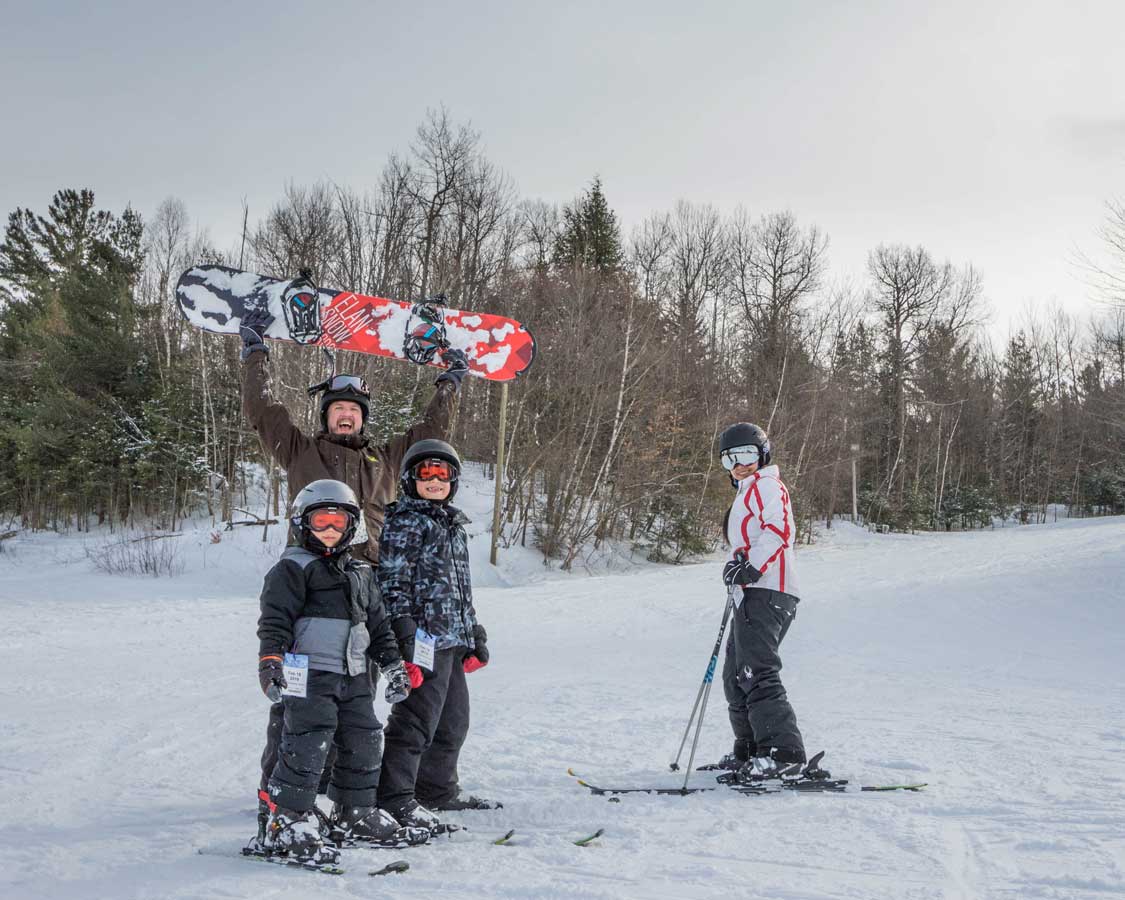 A family laughing while posing for a ski photo in New York State