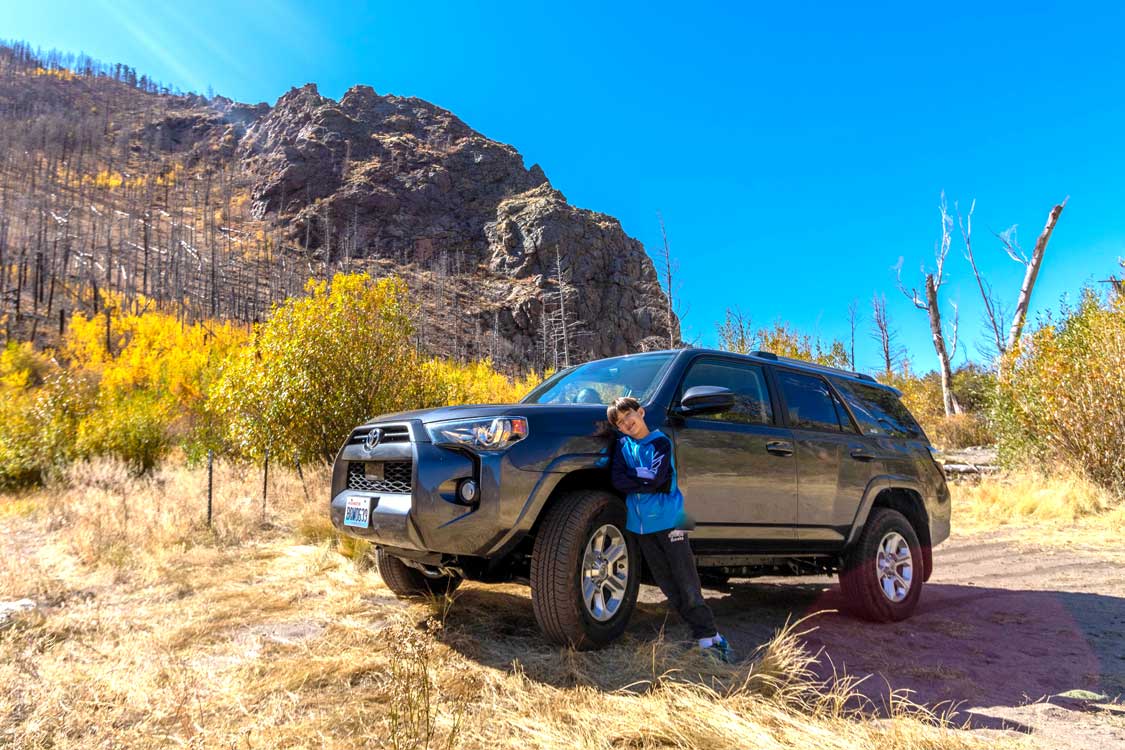 Boy leaning against an SUV in Great Sand Dunes National Park