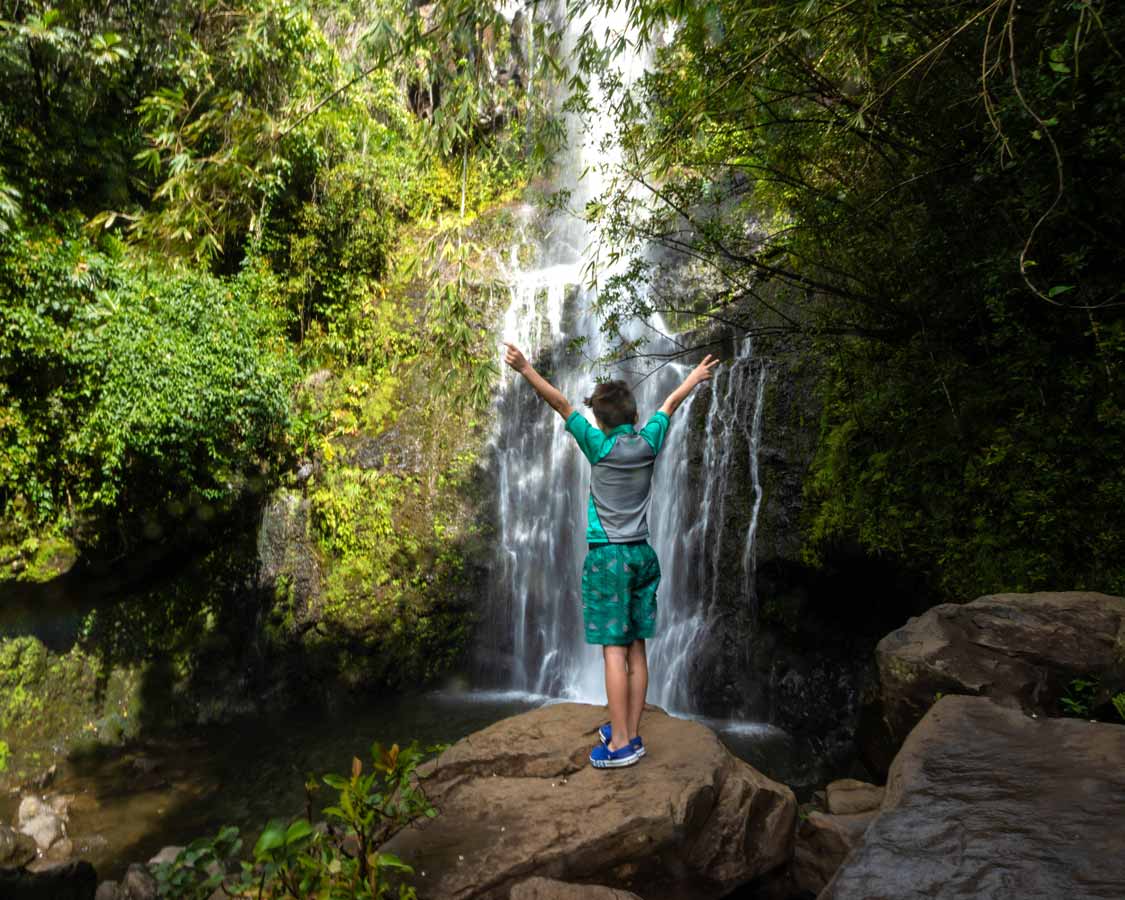 Where to stay in East Maui boy standing by a waterfall