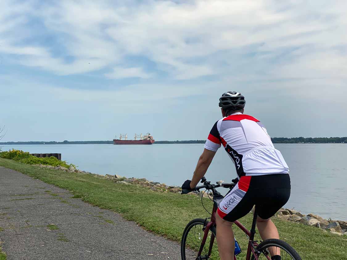 Cyclist watches a cargo ship in the St. Lawrence River