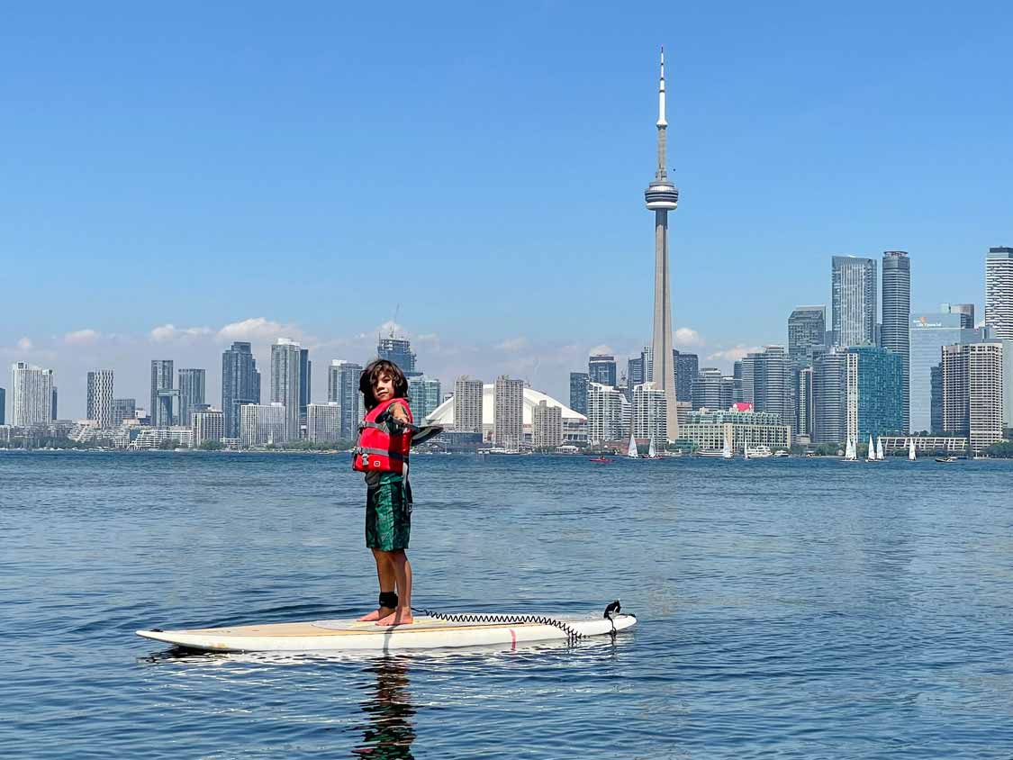 A boy stand up paddleboarding at the Toronto Islands