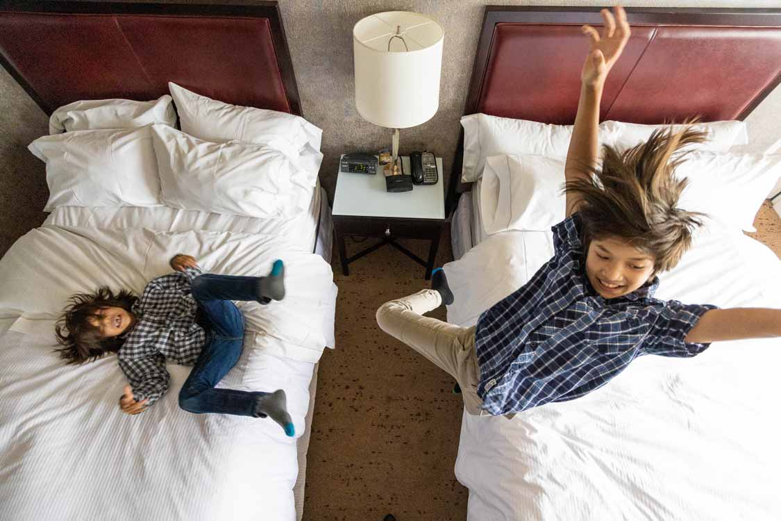 Kids jumping on a bed at the Westin Harbour Castle in Toronto