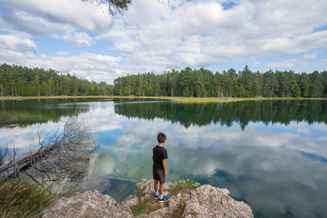 A boy stands on the shores of Lake McGinnis Miromictic Lake
