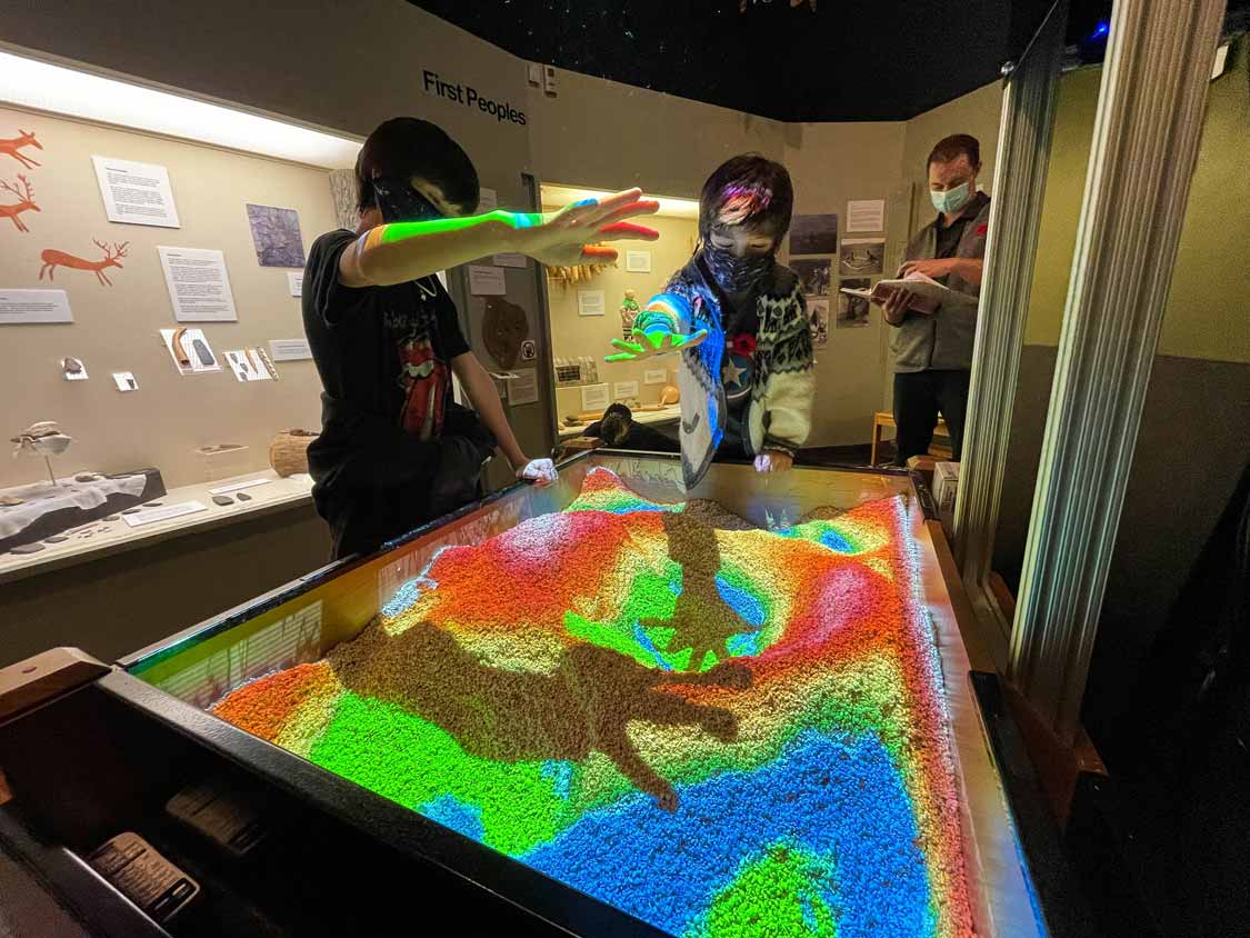 Two boys play with a geology sand pit at Peterborough Museum and Archives