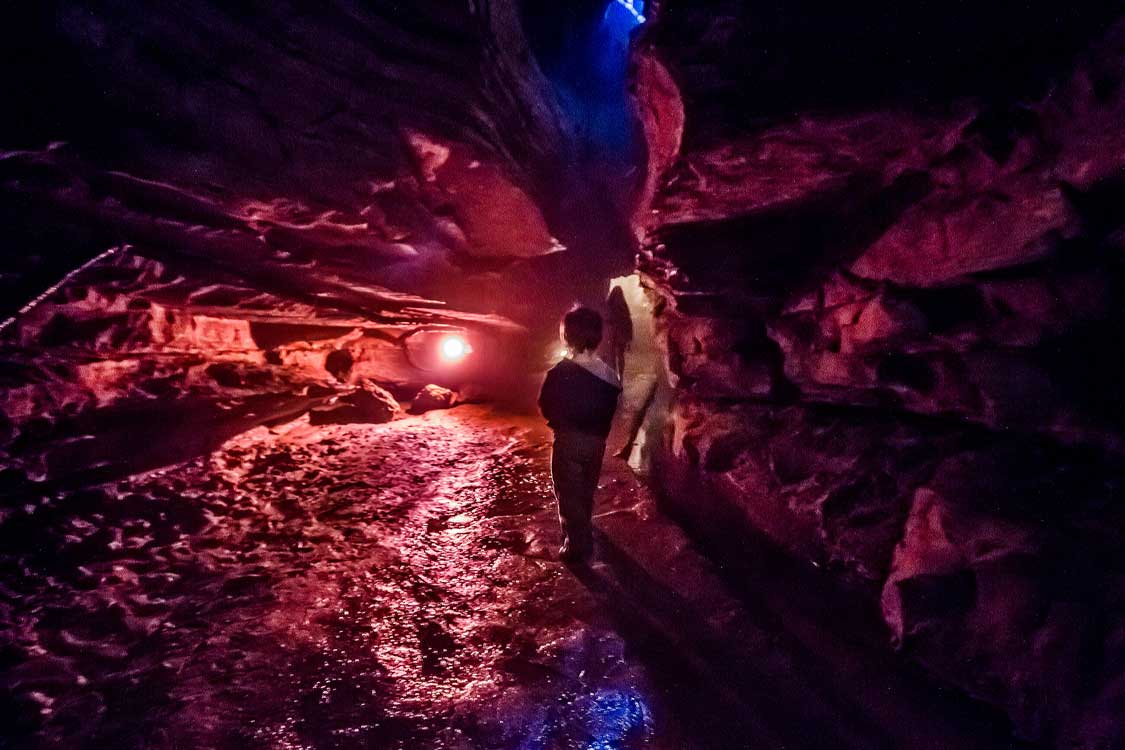 Young boy walking through and eerily lit cave