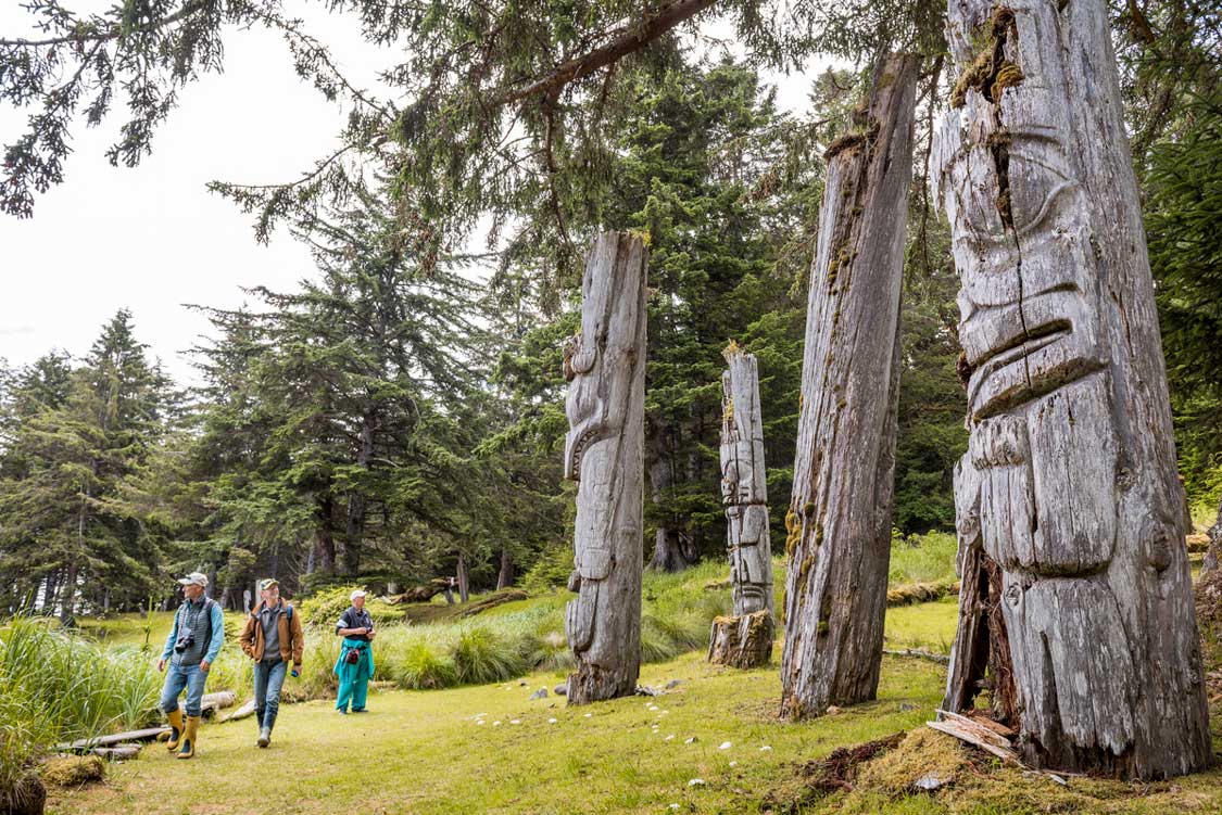 Visitors walk among totems in Gwaii Haanas National Park in Haida Gwaii