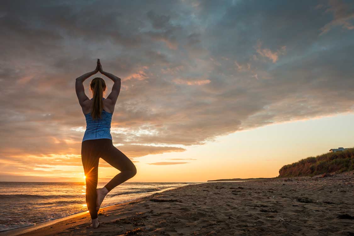 Woman doing yoga on the beach at Prince Edward Island National Park