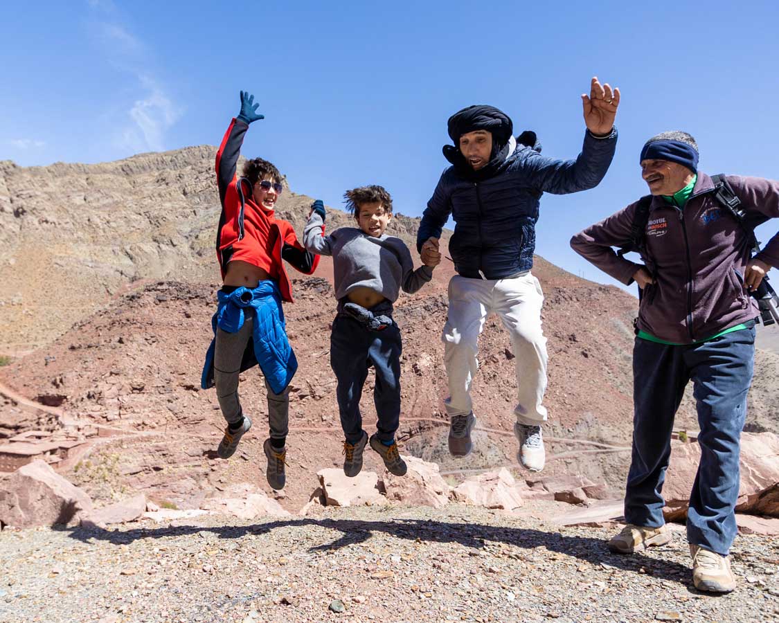 Boys jumping with their guide while hiking the High Atlas Mountains in Morocco