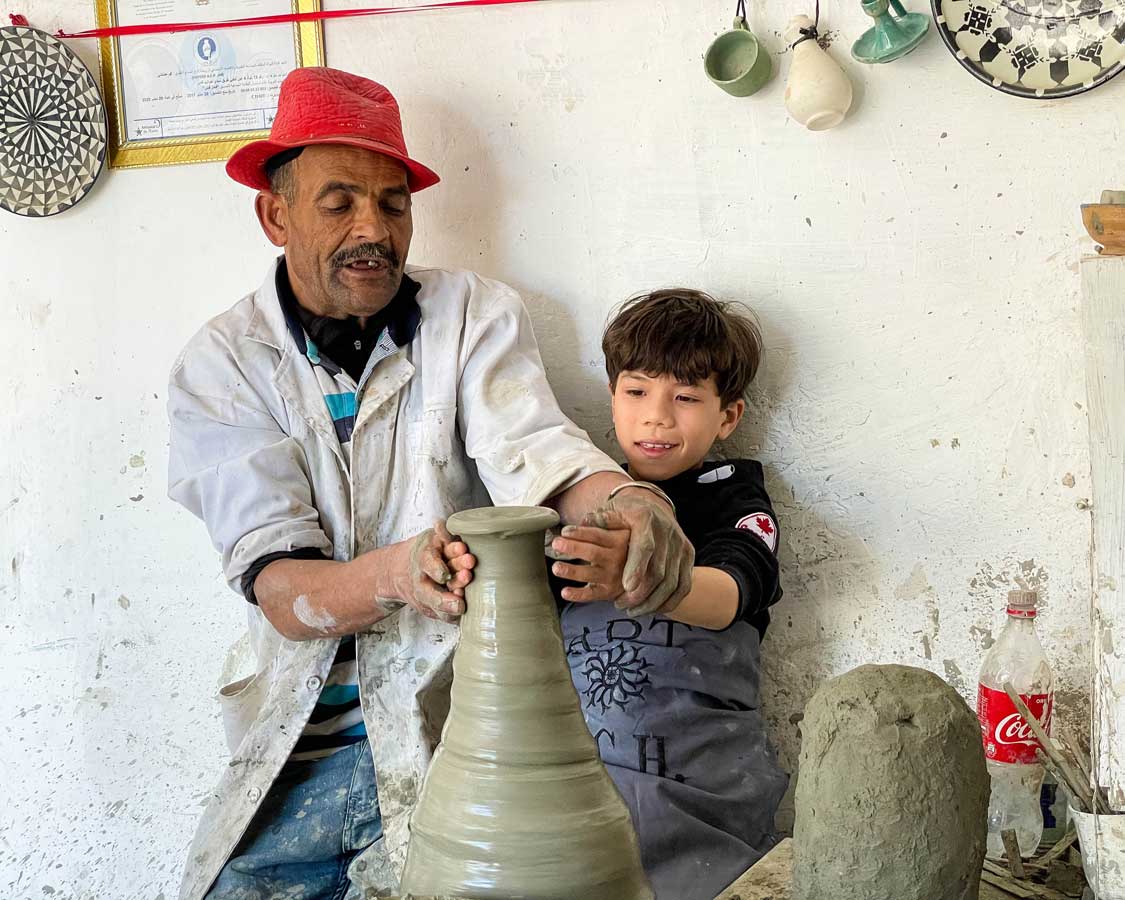 Boy making pottery with a potter in Fes, Morocco