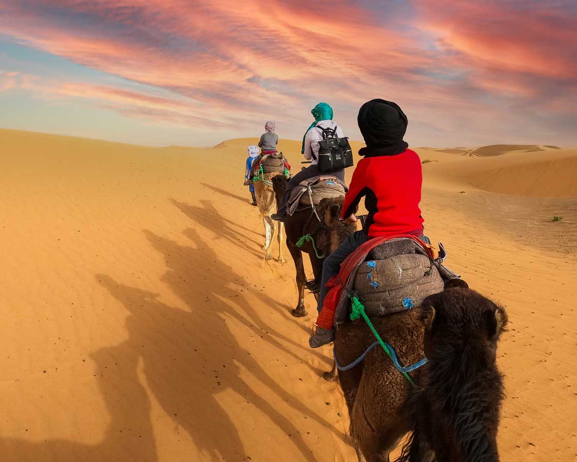 Family riding camels through the Sahara desert