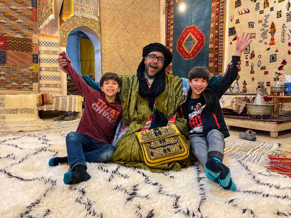 Two boys with a Moroccan rug seller in Ouarzazate