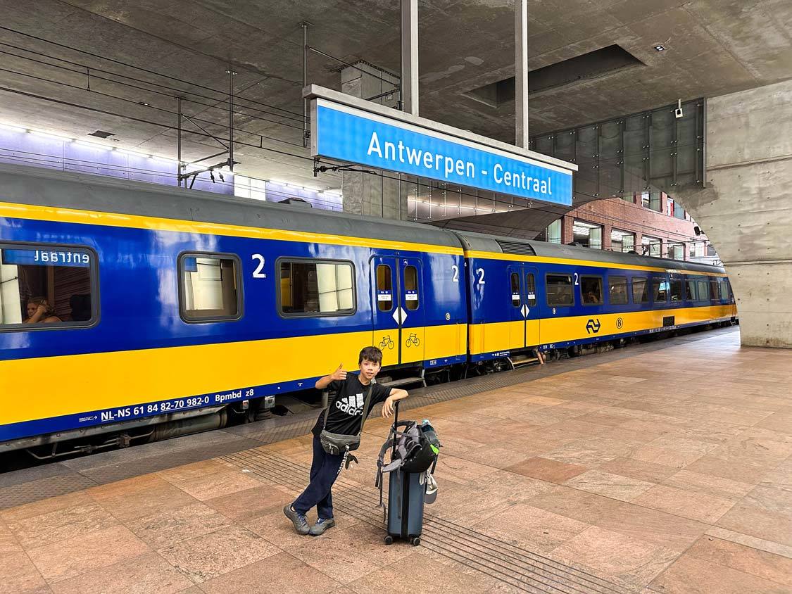 A boy leans on his carry on luggage while boarding a train in Antwerp, Belgium