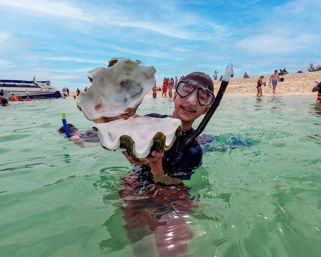A boy holds a giant clam near Koh Lanta, Thailand