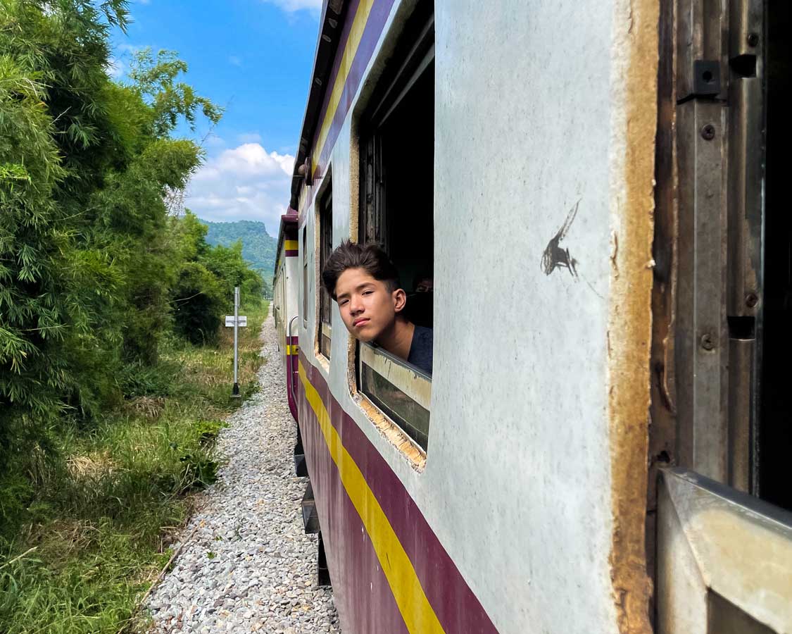 Boy riding the Death Railway in Kanchanaburi, Thailand