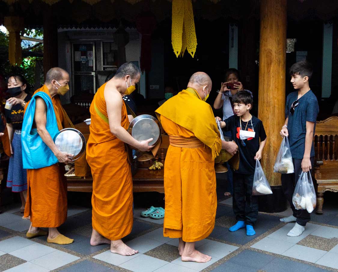 Children giving offerings to Buddhist monks in Thailand