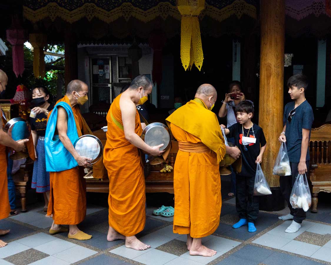 Children paying ohms to Buddhist monks at Dai Wat Monastery