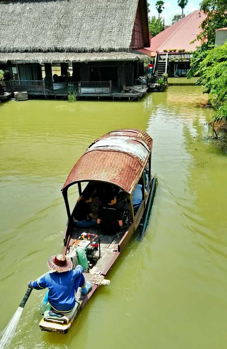 Longtail boat in green water entering the Ayutthaya floating market